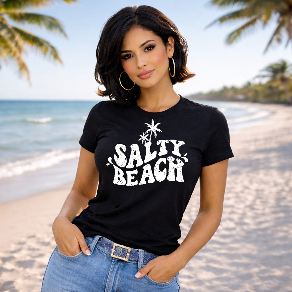 Woman wearing a black t-shirt with 'Salty Beach' text on a beach