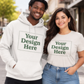 Male and female models wearing custom hoodie and t-shirt with Your Design Here placeholder design on urban street background.